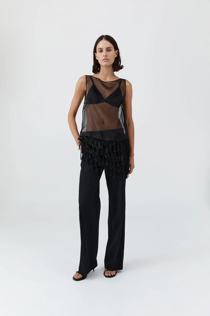 Woman wearing a black sheer top and pants on a white background