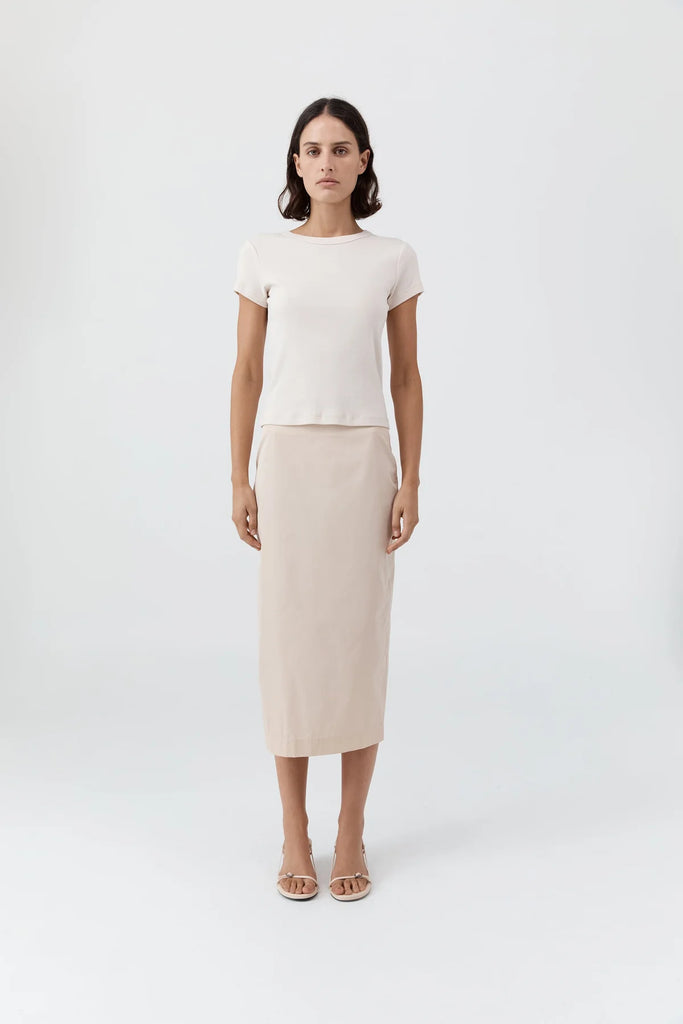 Woman wearing a white top and beige skirt on a white background