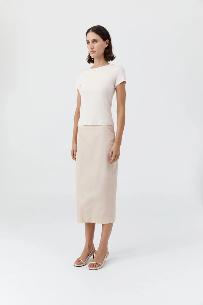 Woman wearing a white top and beige skirt on a white background