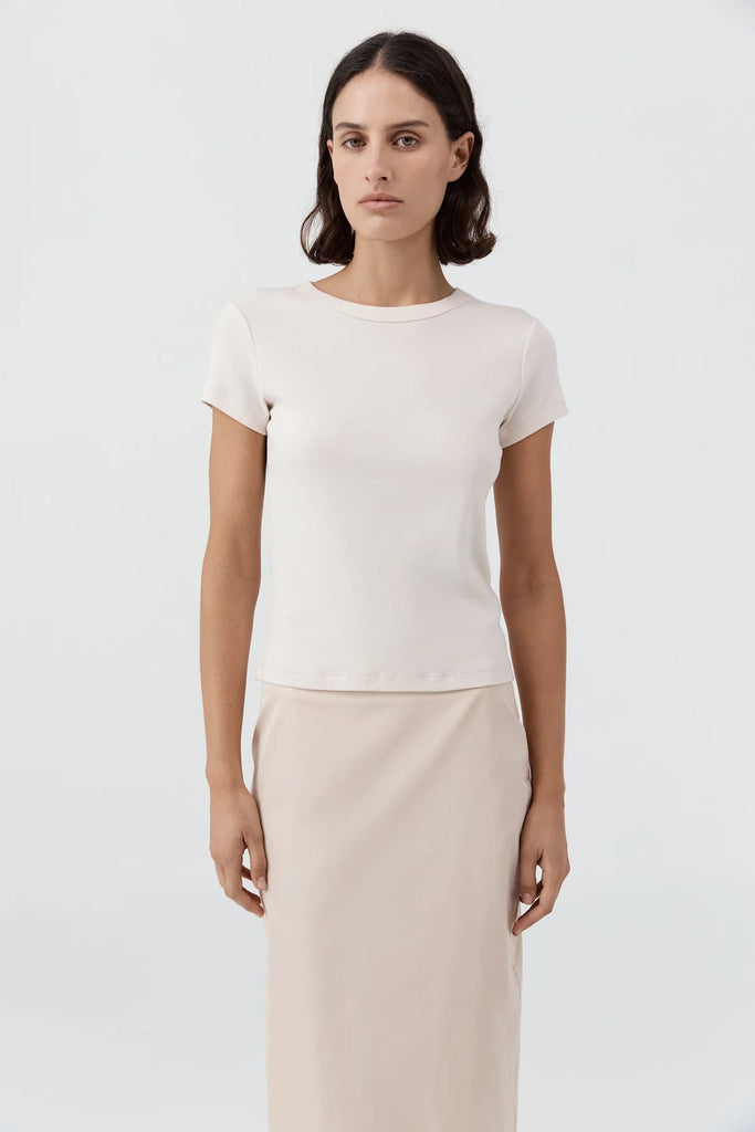 Woman wearing a white t-shirt and beige pants against a white background