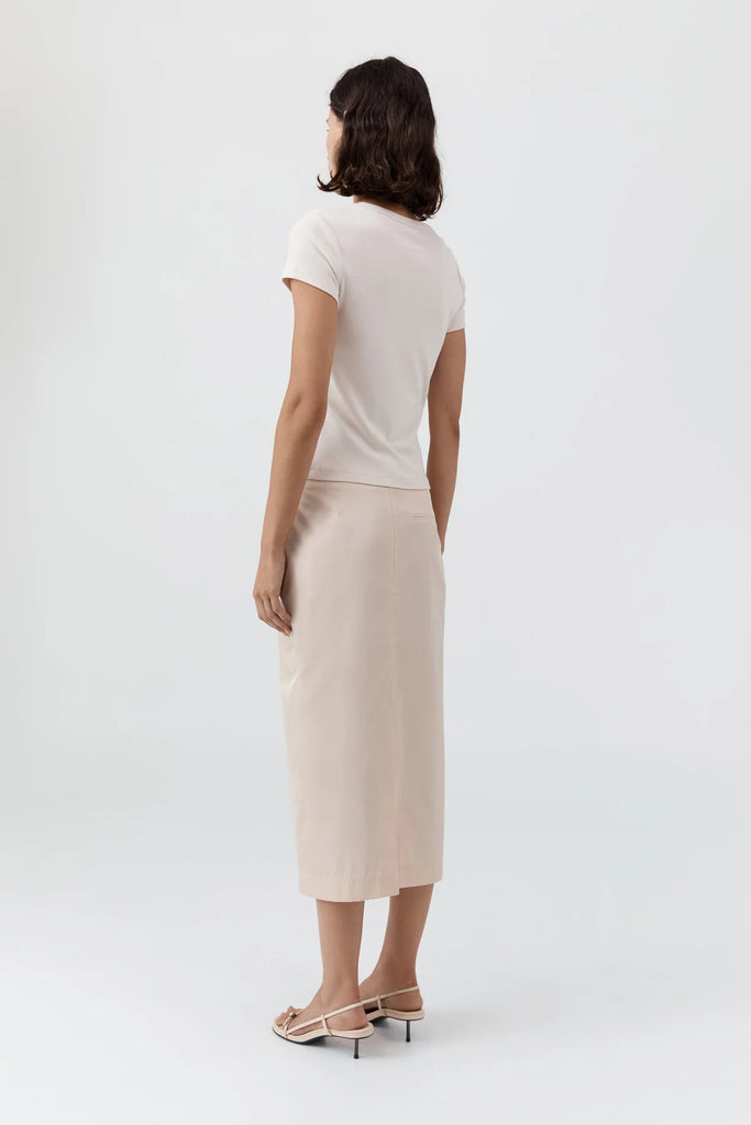 Woman wearing a white top and beige skirt on a white background