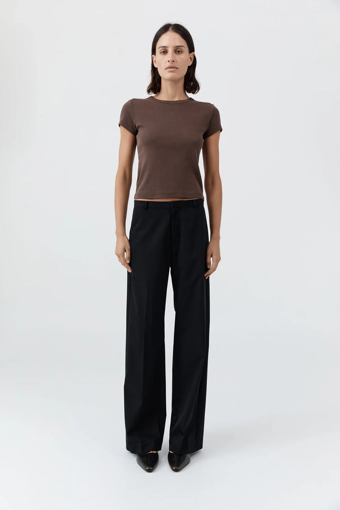 Woman wearing a brown t-shirt and black pants on a white background