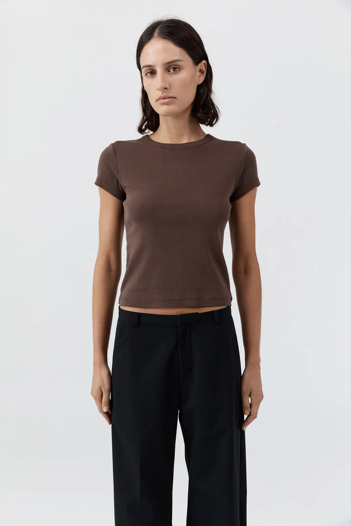 Woman wearing a brown t-shirt and black pants on a white background
