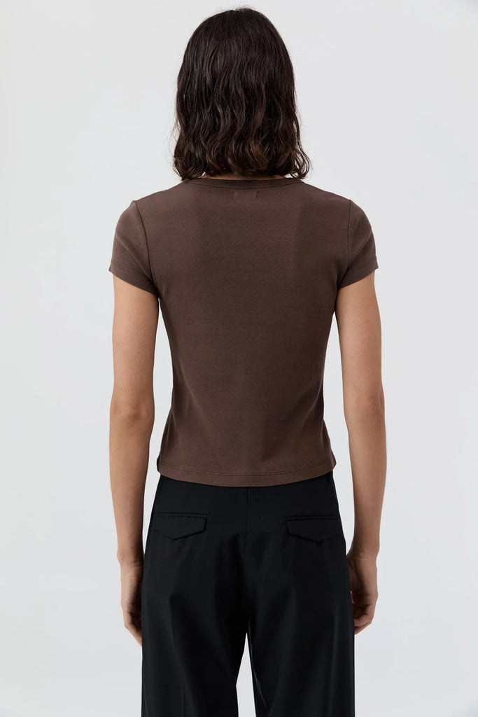 Person wearing a brown t-shirt and black pants on a white background