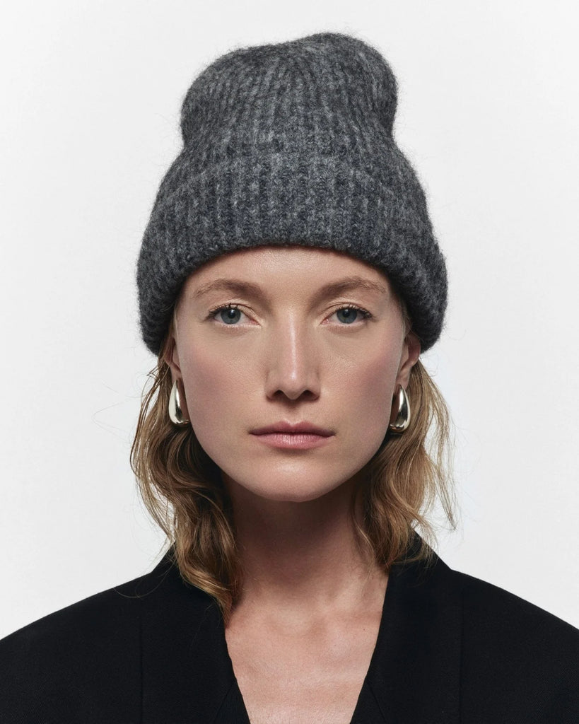 Person wearing a gray knit beanie on a white background