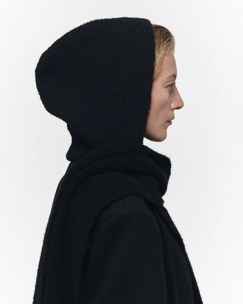 Person wearing a black knitted hood against a white background