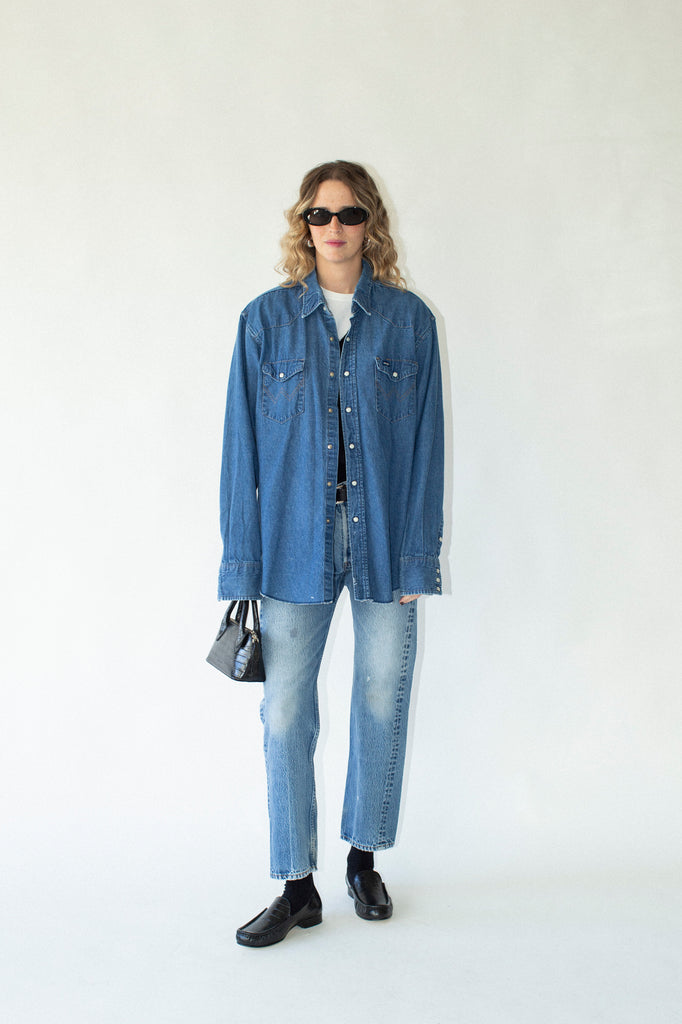 Person wearing a blue denim shirt and jeans on a white background