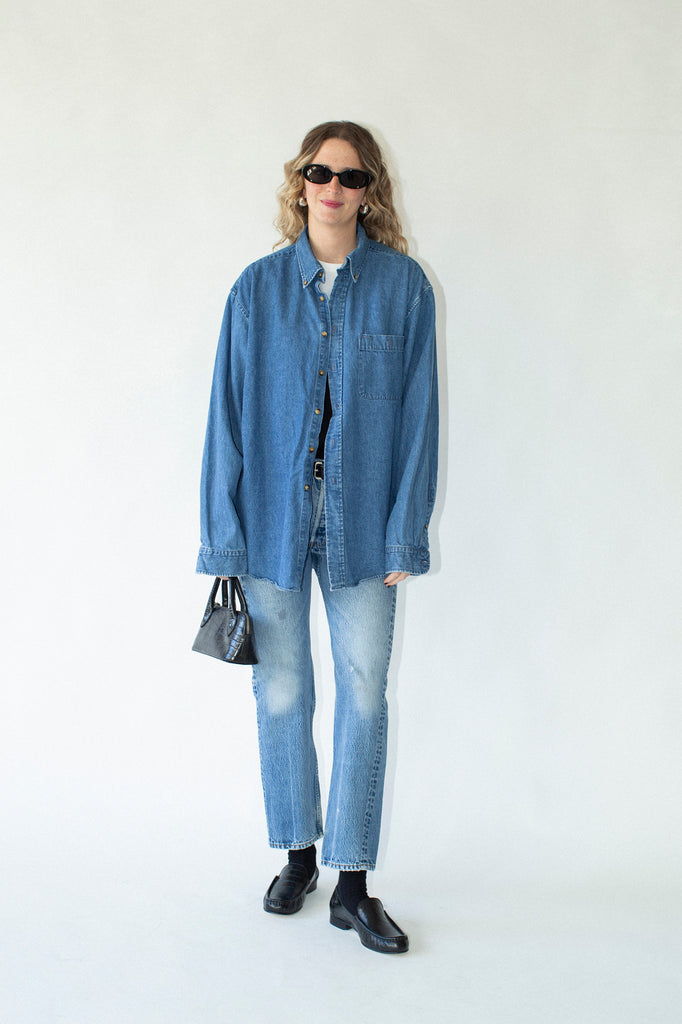 Person wearing a blue denim shirt and jeans on a white background