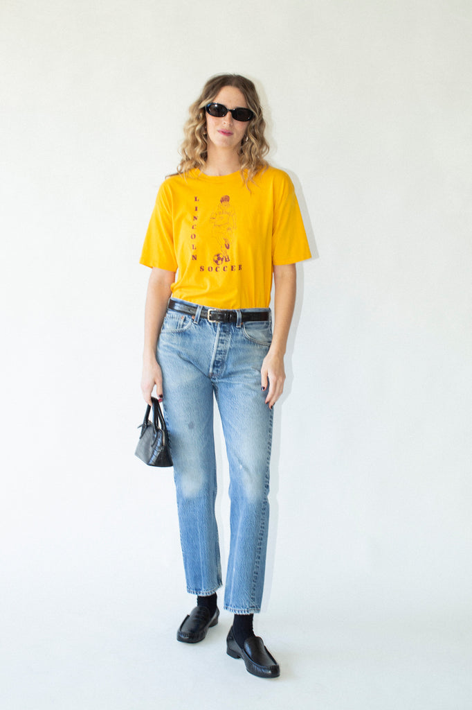Person wearing a yellow t-shirt and blue jeans on a white background