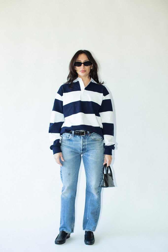 Person wearing a navy and white striped shirt with blue jeans on a white background