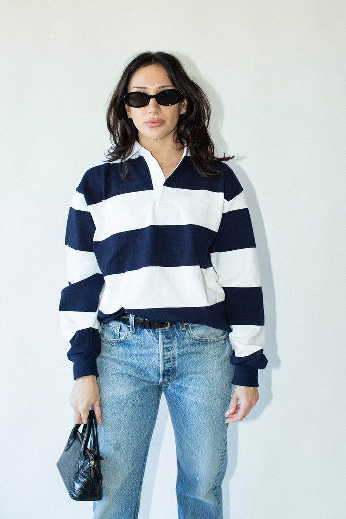 Woman wearing a navy and white striped sweater with blue jeans against a white background