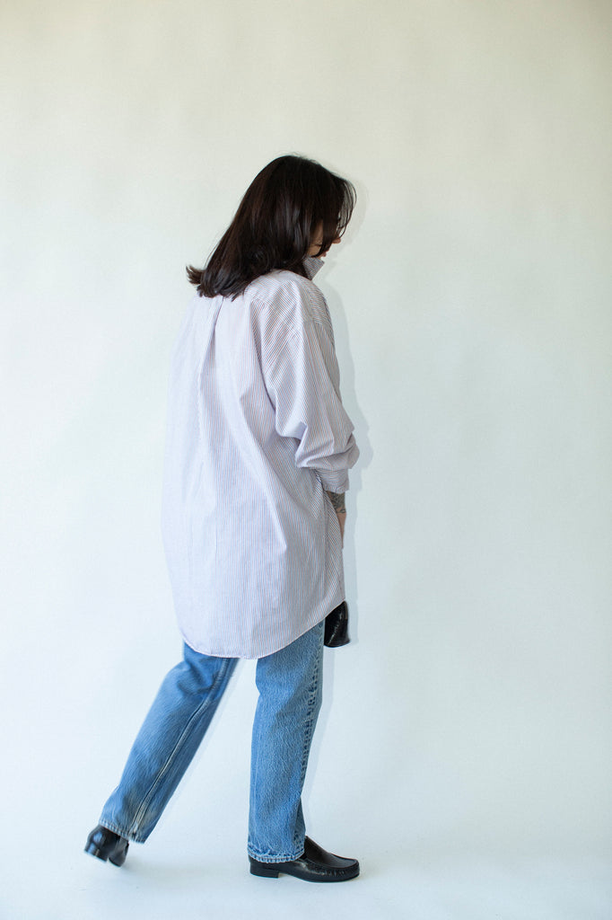 Person wearing a light-colored shirt and blue jeans against a white background