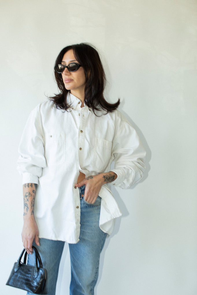 Person wearing a white shirt and blue jeans against a plain background