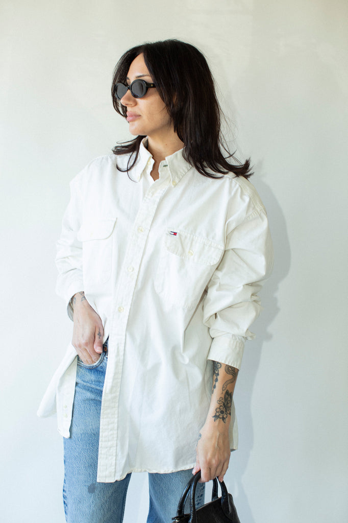 Person wearing a white shirt and blue jeans against a plain background