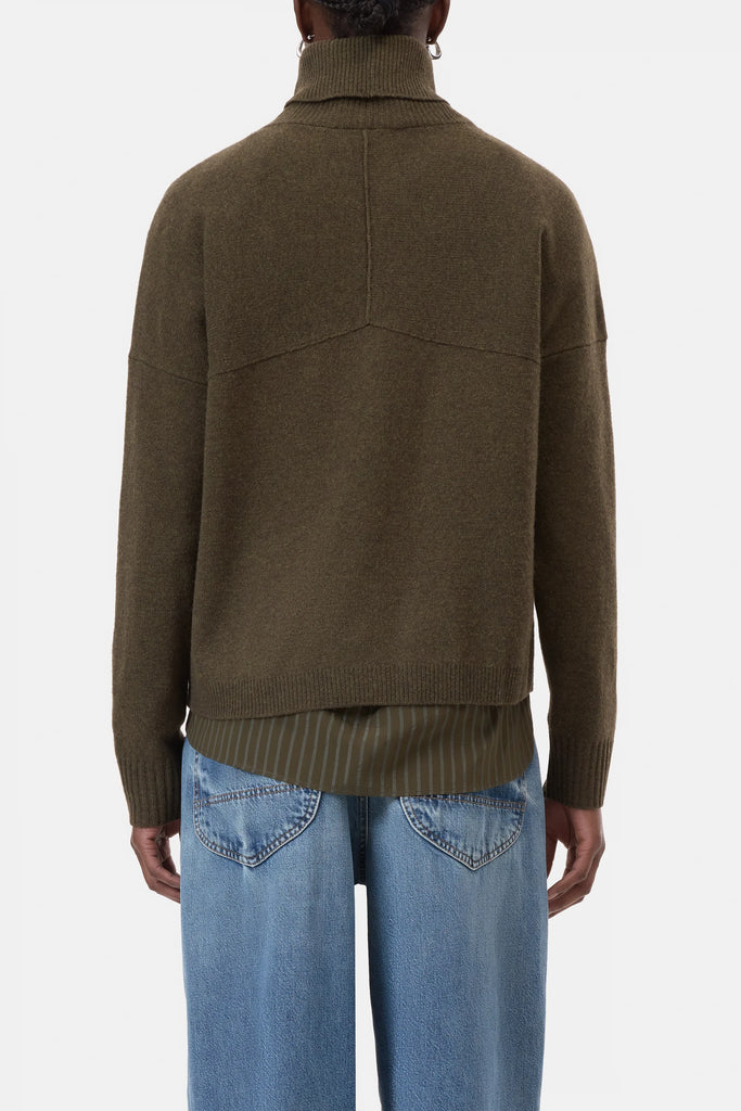 Person wearing a brown sweater and blue jeans on a white background