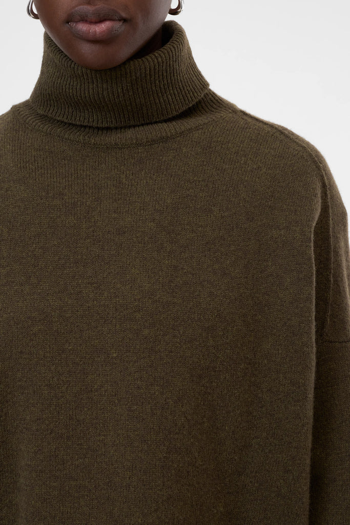 Close-up of a person wearing a brown turtleneck sweater on a white background