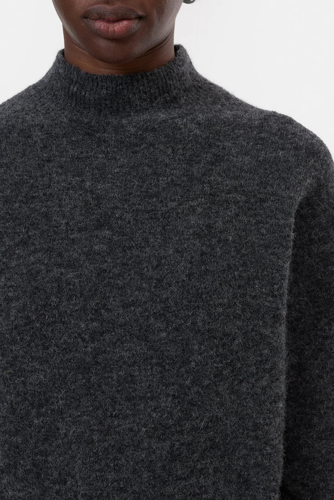 Dark gray turtleneck sweater worn by a person on a light gray background