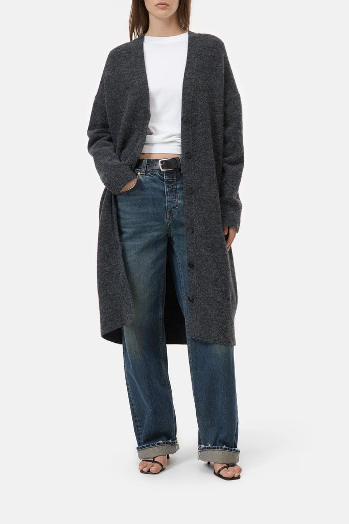 Person wearing a long dark gray cardigan, white shirt, and blue jeans on a white background