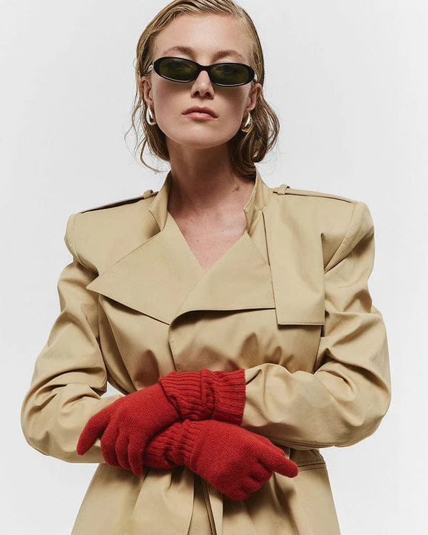 Person wearing a beige trench coat and red gloves with a plain background