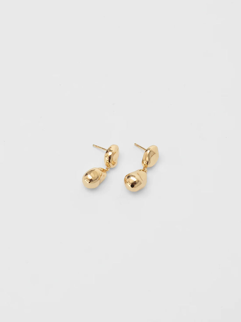 Pair of gold earrings on a light beige background