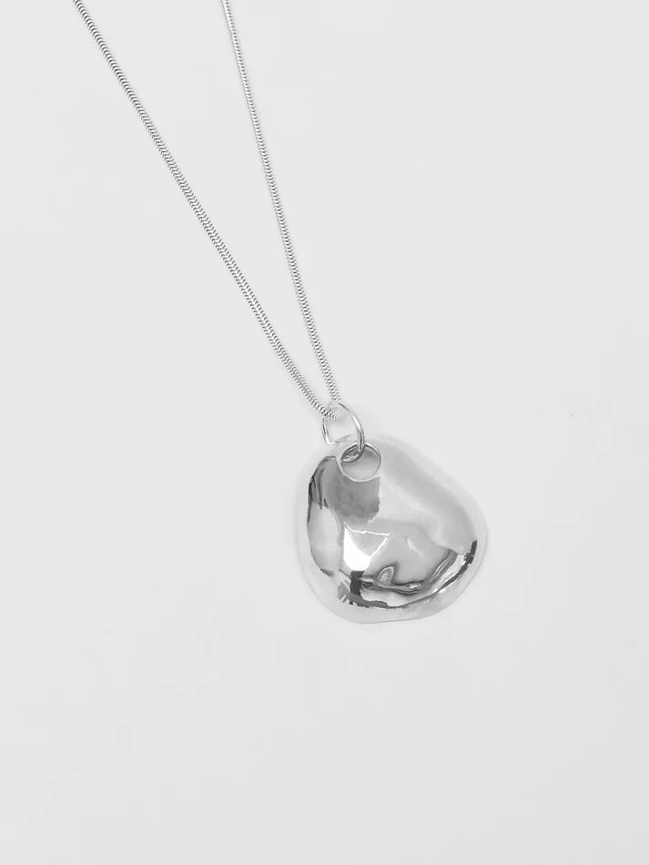 Silver necklace with a heart-shaped pendant on a light gray background